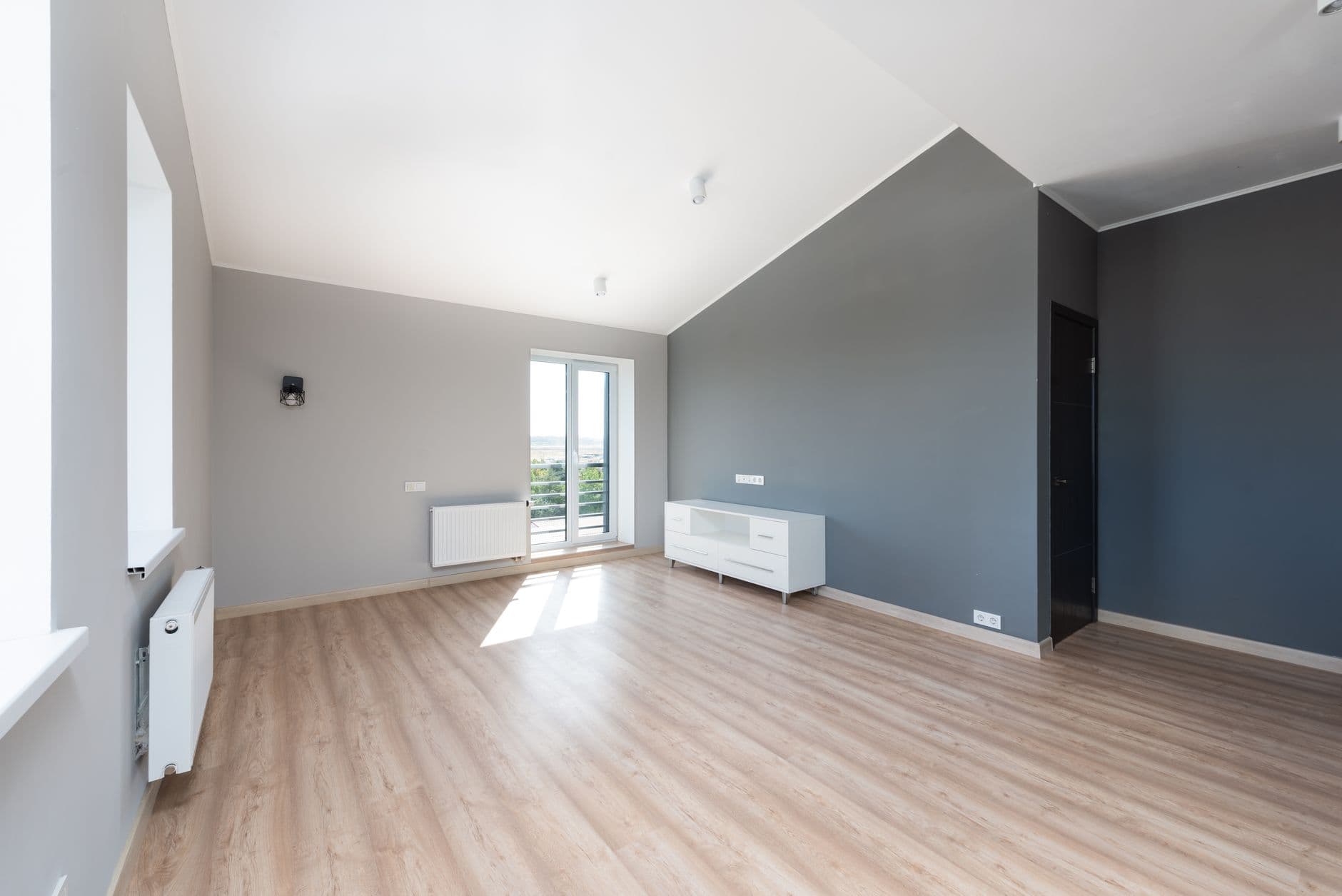 Salón de un apartamento moderno reformado con acabados de alta calidad, suelo de madera, cocina integrada y grandes ventanales, listo para entrar a vivir