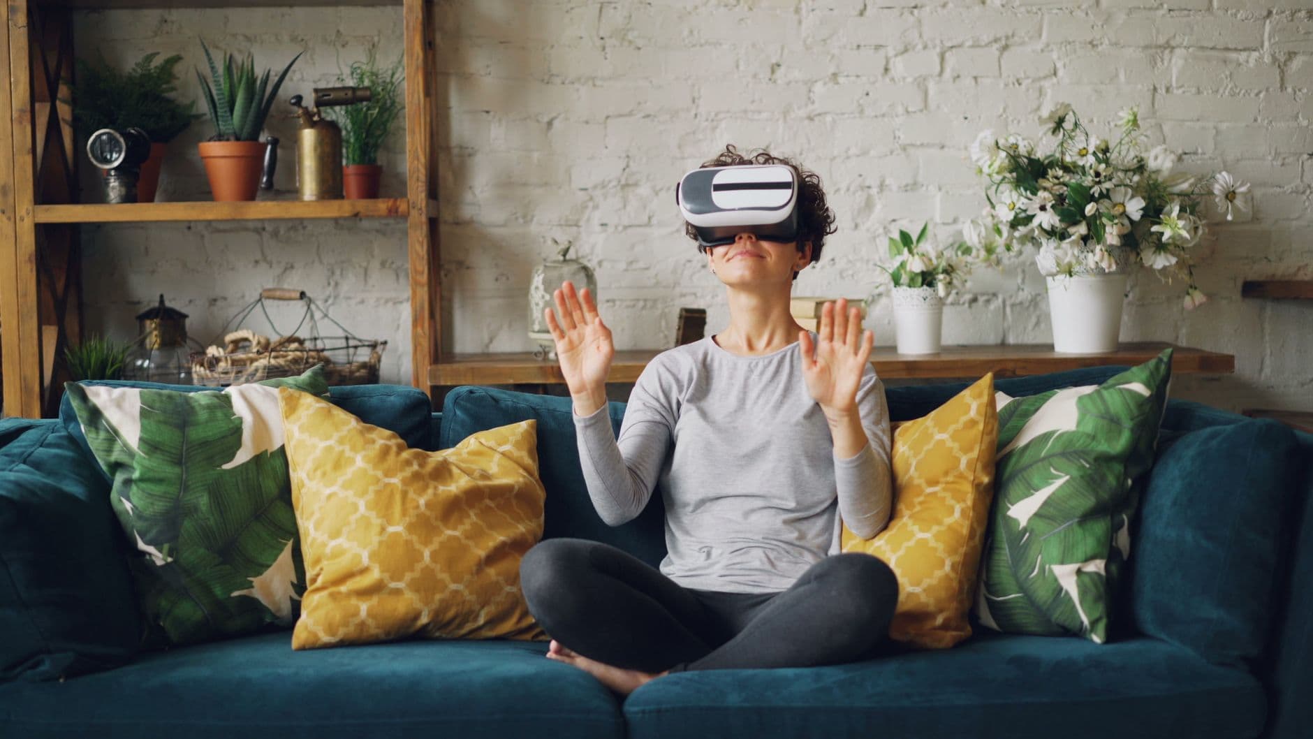 Una persona utilizando gafas de realidad virtual para explorar un apartamento moderno y luminoso con ventanales grandes.