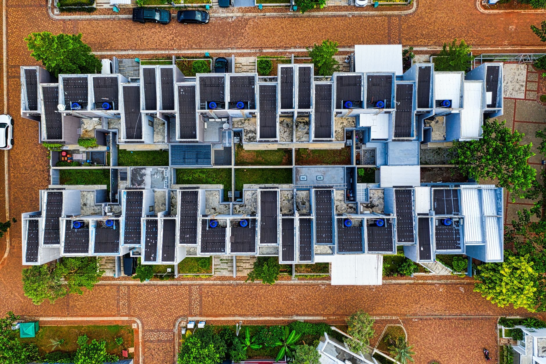 Modern apartment building in Spain with solar panels on the roof, green walls, and landscaped outdoor area, representing sustainable residential living