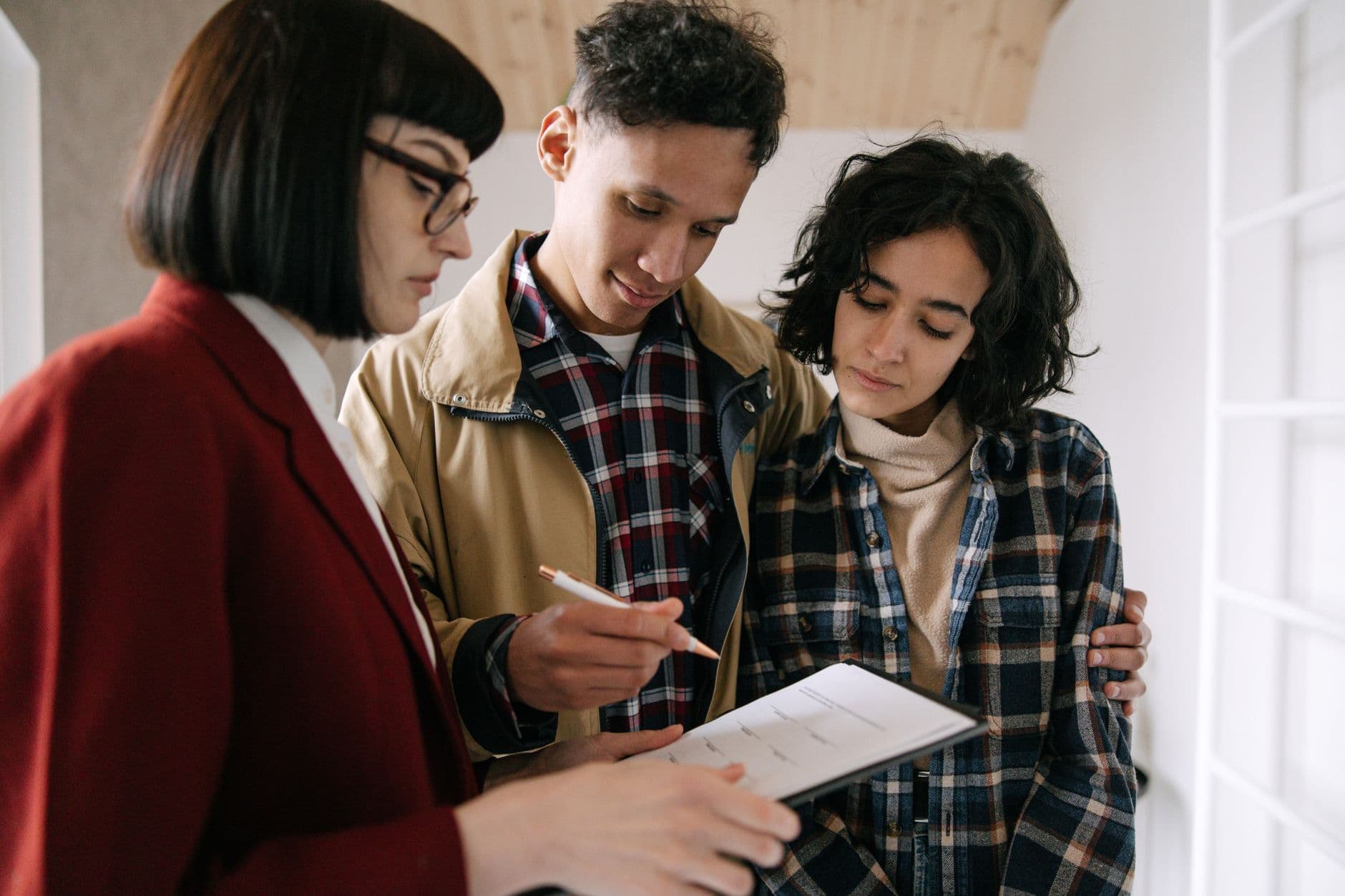 FAMILY AND FRIENDS DISCUSSING HOMEOWNERSHIP PLANS WITH DOCUMENTS IN A MODERN APARTMENT
