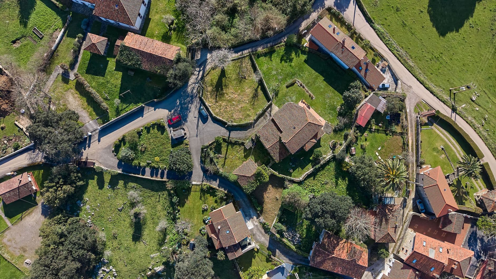 Vista aérea de un barrio residencial moderno en el norte de España, con edificios de baja altura integrados en entorno verde montañoso, transmitiendo calidad de vida y sostenibilidad