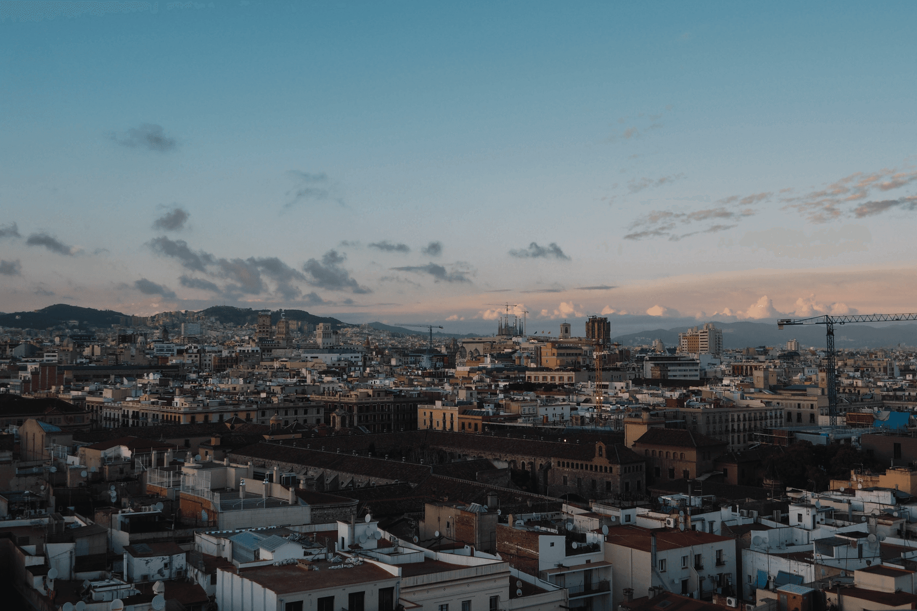Una vista aérea moderna de una ciudad española con edificios contemporáneos y zonas verdes bajo una luz de atardecer cálida.